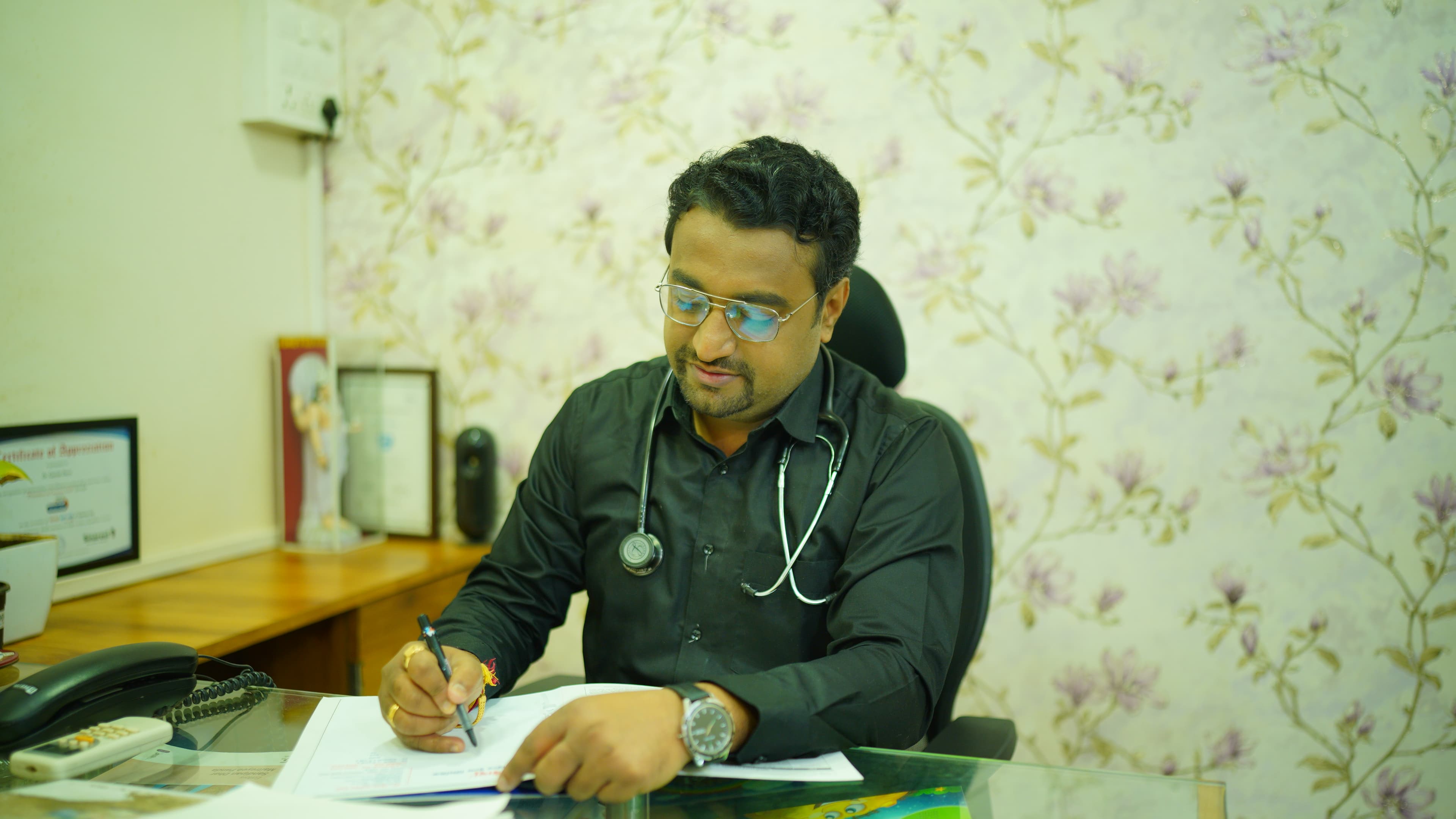 Dr. Gaurav Deore (MD Pediatrics) writing a prescription at his consultation desk
